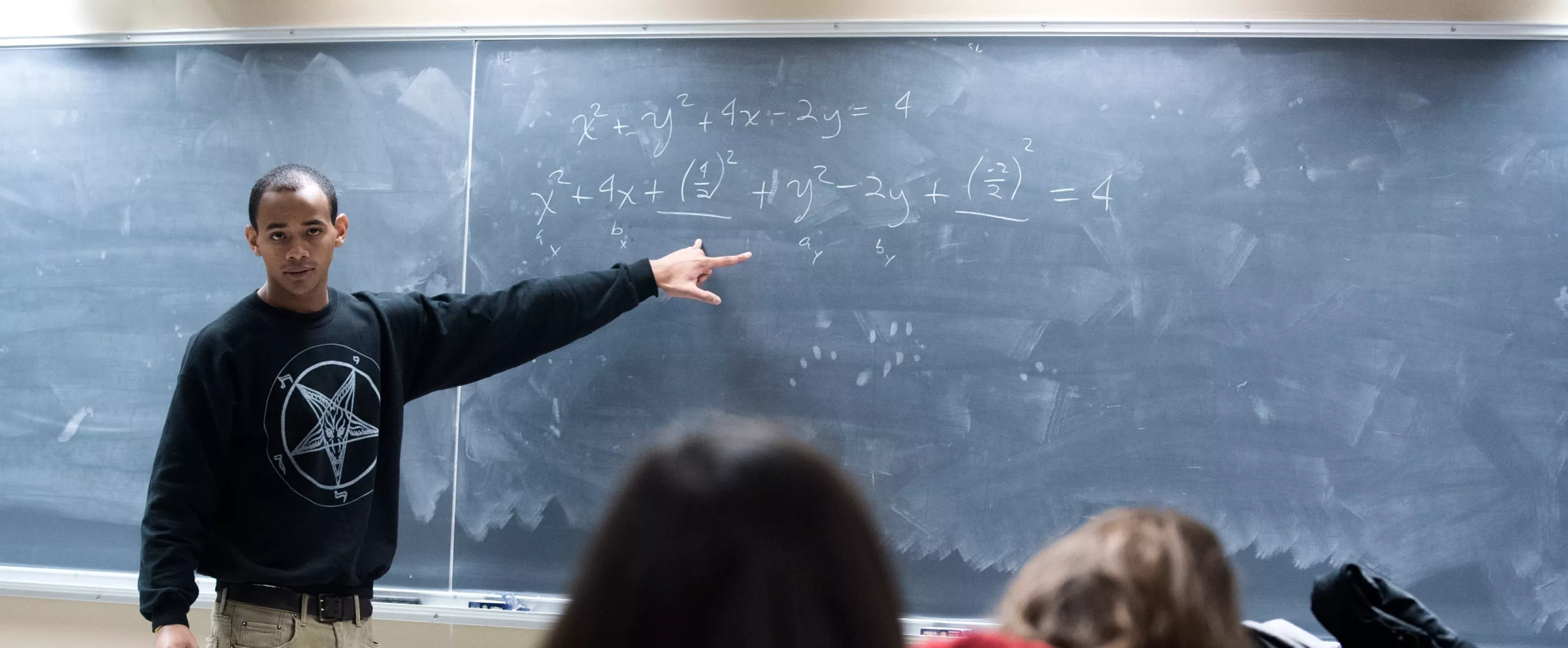 Professor teaches students math problems using the chalk board