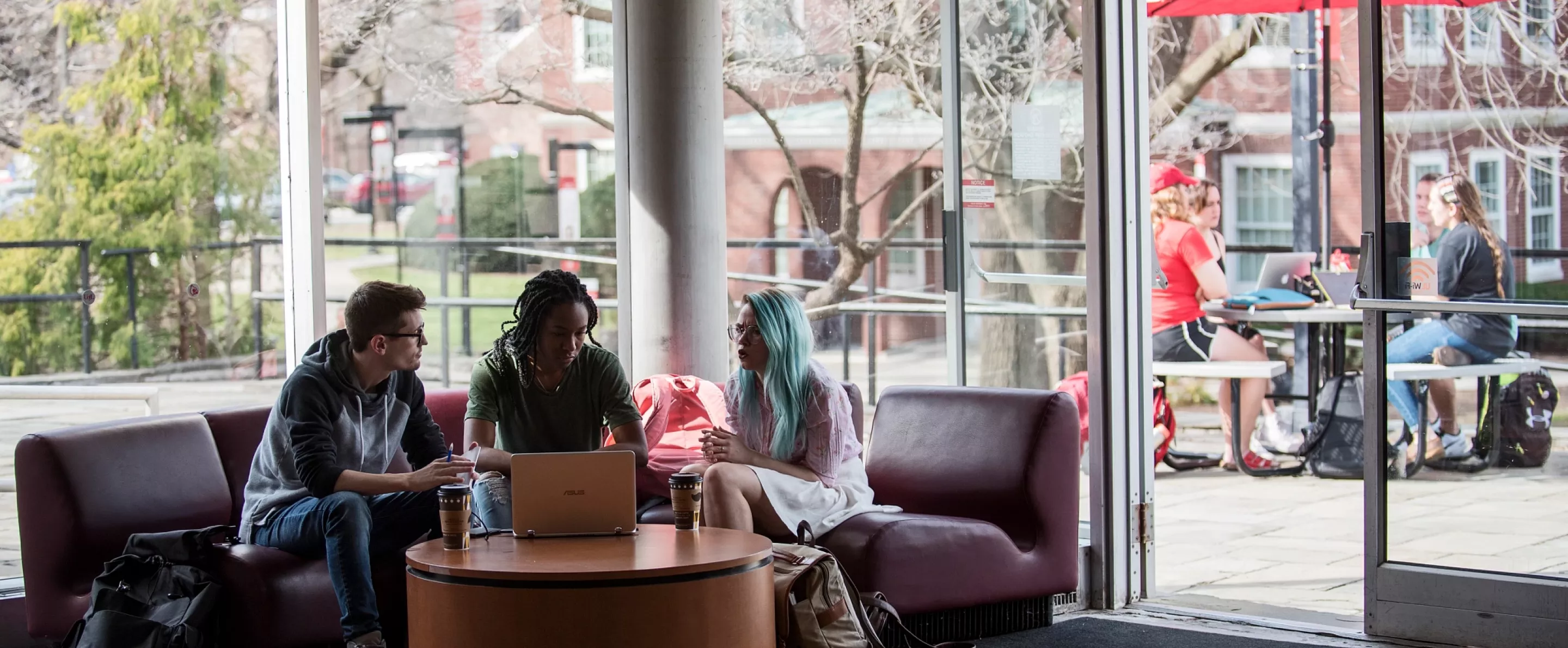 Three fine art students working together in the lobby of Schneider Hall
