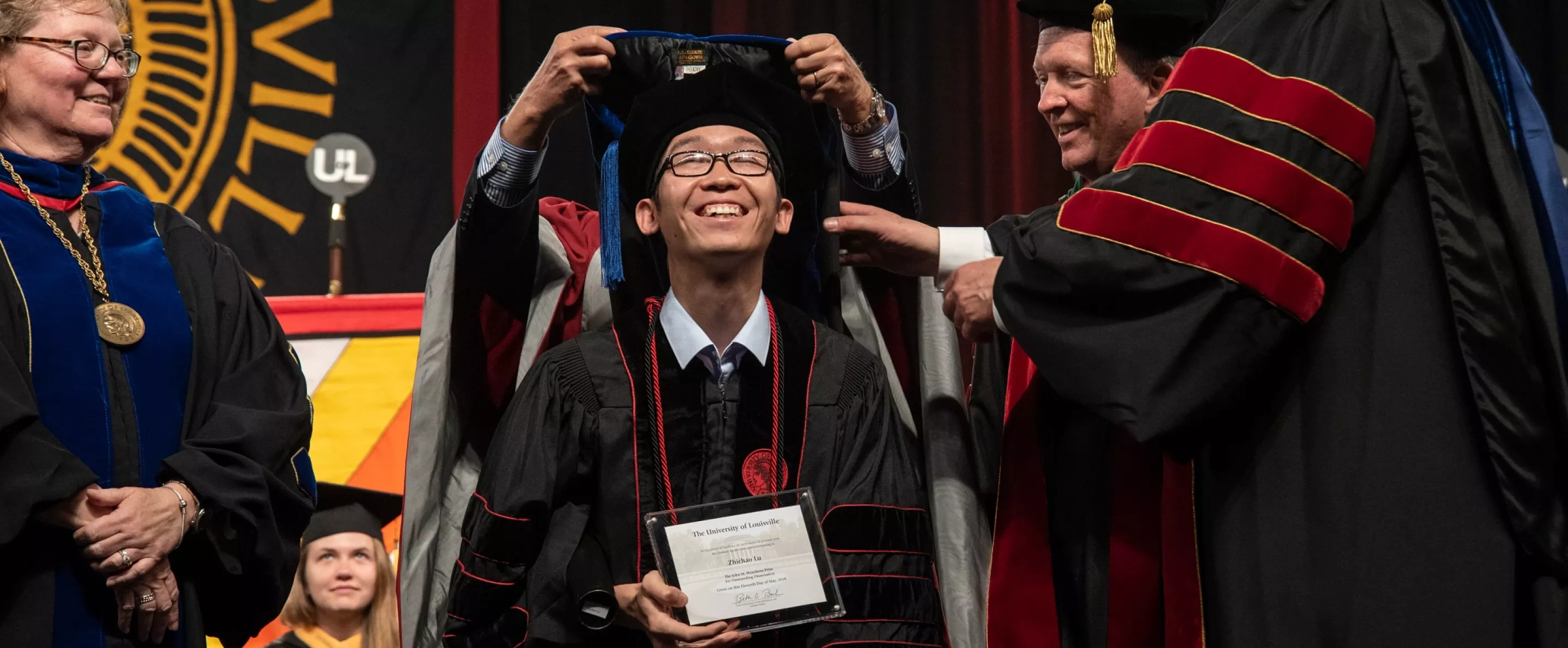 PHD student smiles at the Hooding Ceremony
