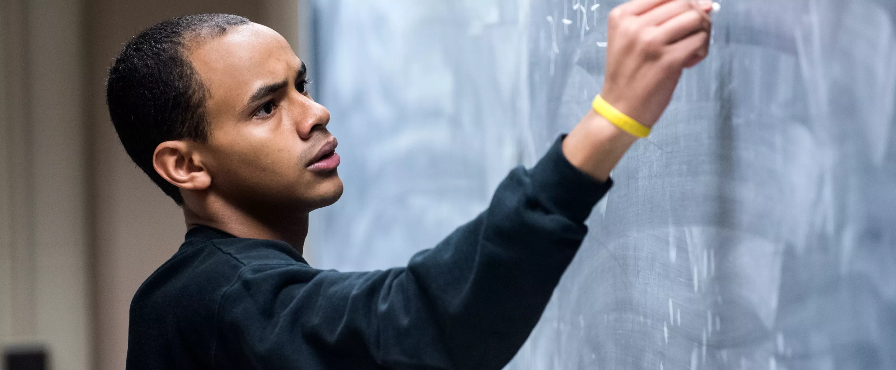 Professor writes out math problems on the chalk board
