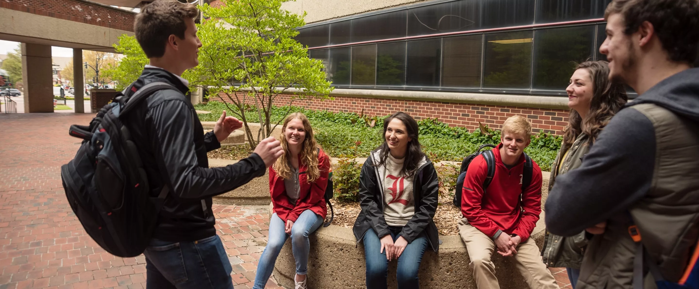 One student tells another group of students a story outside College of Business