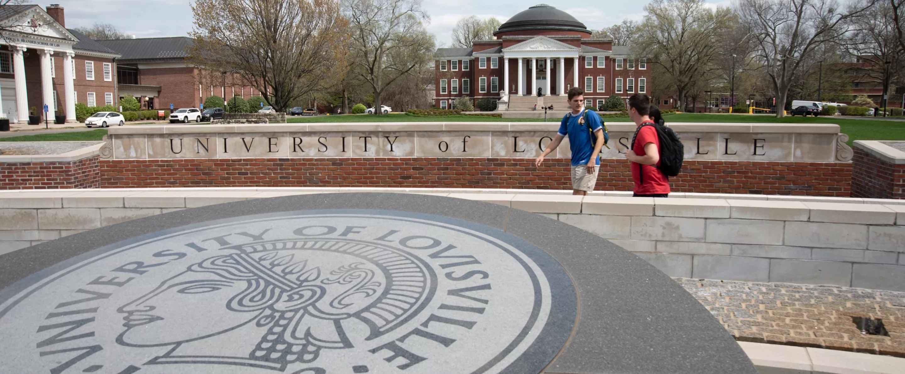 Students walking and talking near the 3rd Street entrance with Grawemeyer Hall and the School of Law buildings in the background