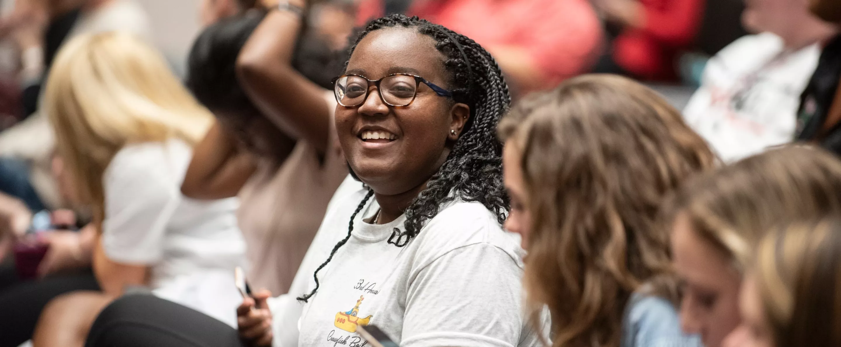 Smiling student in the audience at an Orientation event