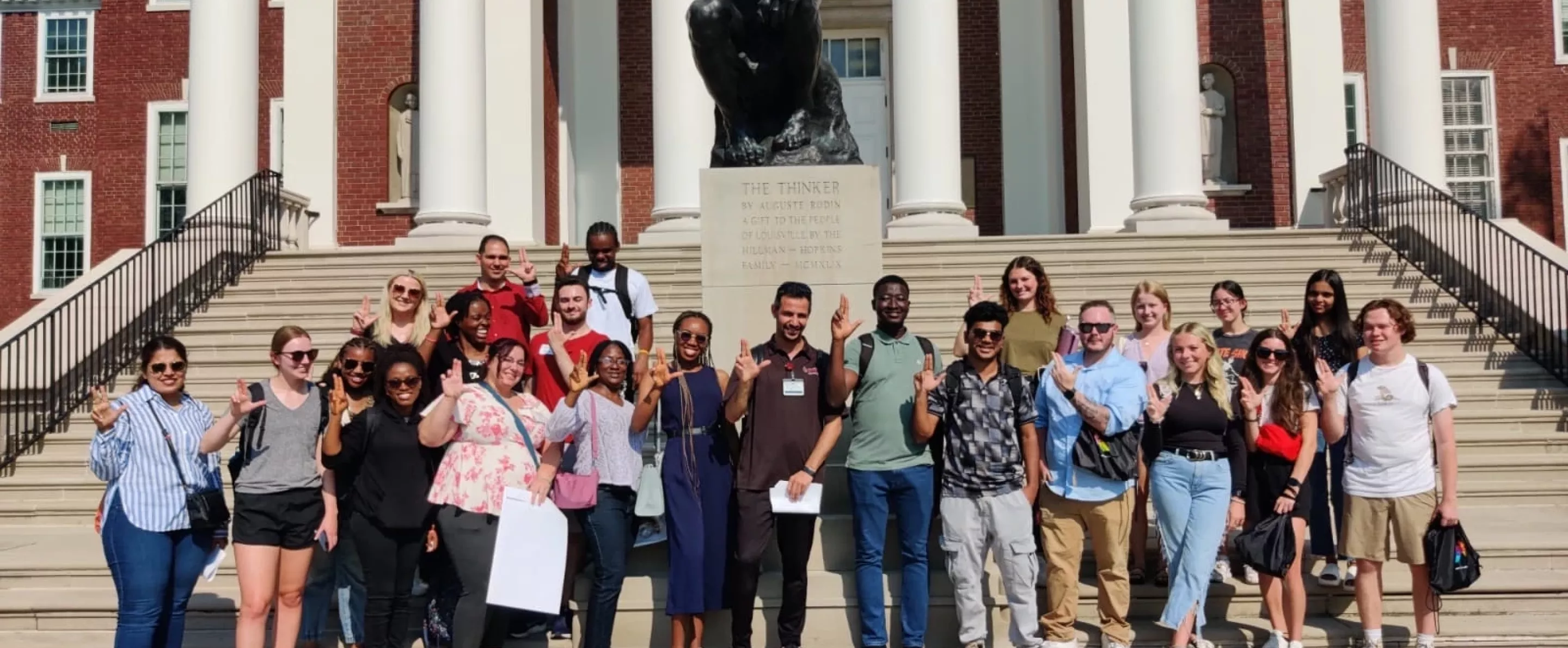 Graduate students posing in front of the Thinker statue.