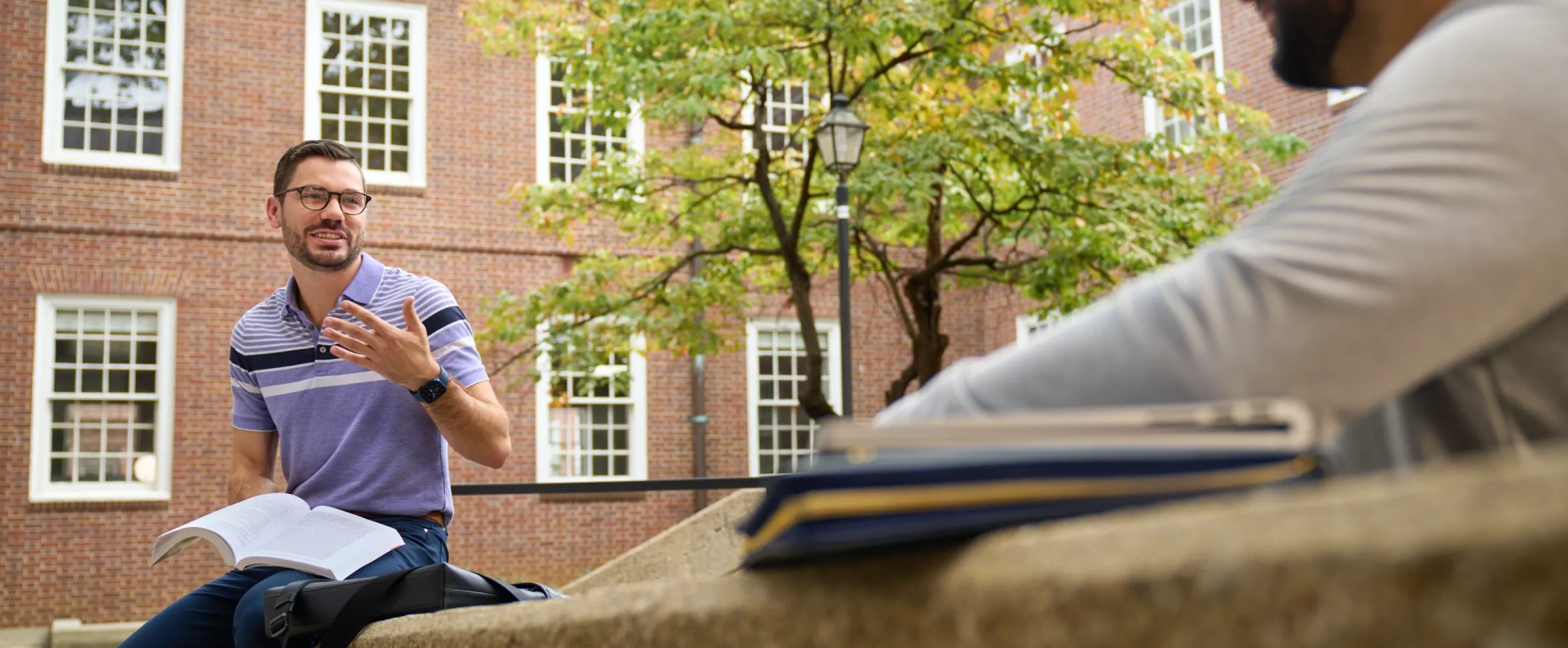 Two students having a socially distanced conversation in the courtyard at the Brandeis School of Law.