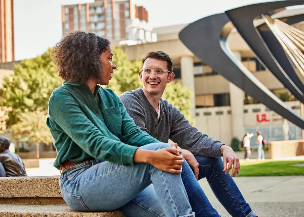 Two students have a pleasant conversation with each other in the HSC courtyard.