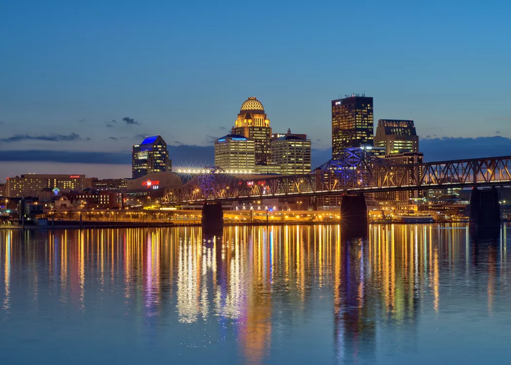Dusk skyline photo of the Louisville waterfront with light reflections in the Ohio River