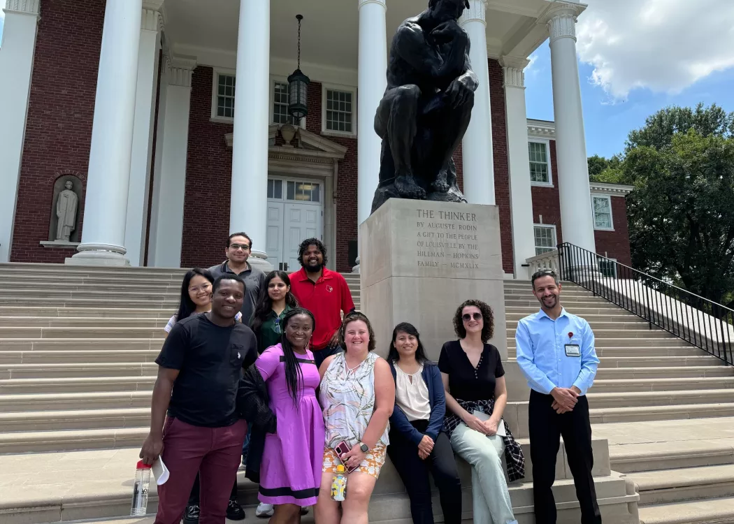 Group of people posing by the Thinker statue.