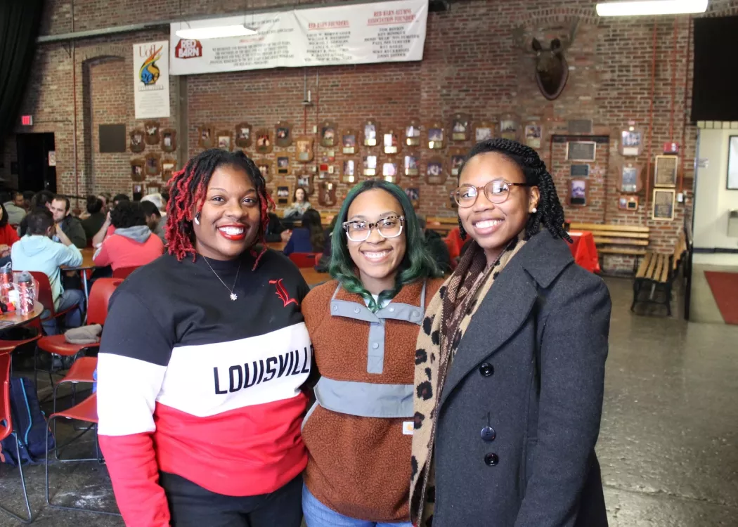 Three graduate students posing at a social event.