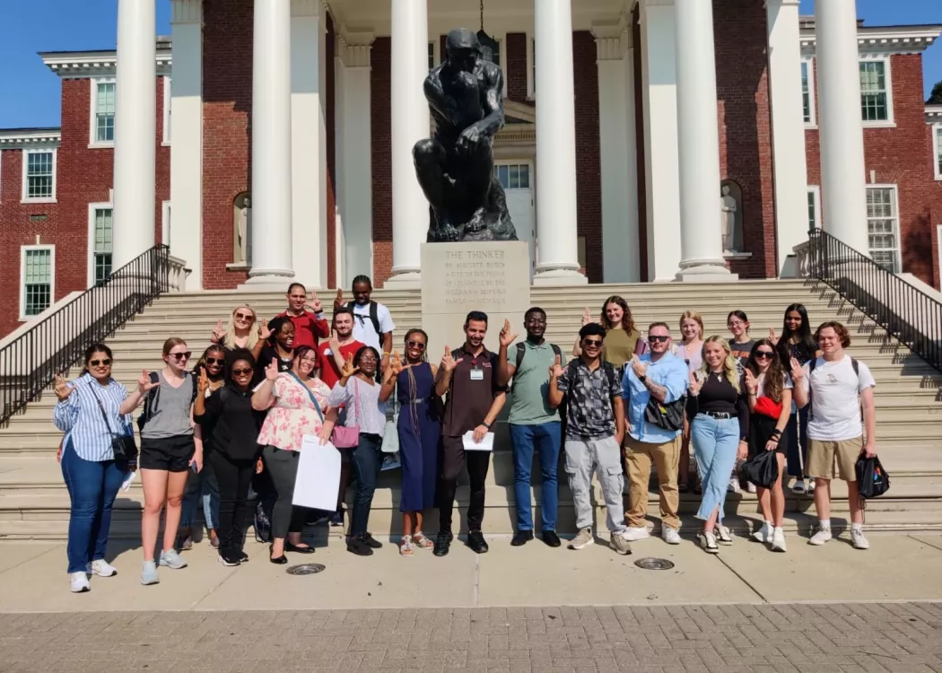 Graduate students posing in front of the Thinker statue.