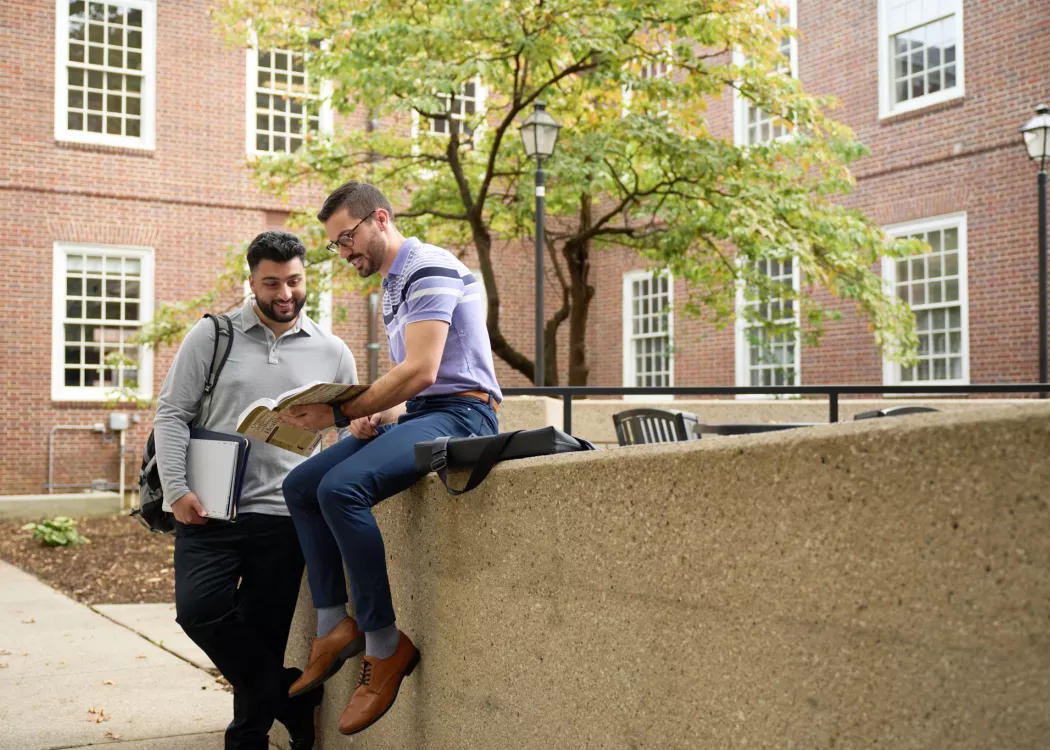 Two students sitting in the courtyard of Brandeis School of Law looking over academic documents.