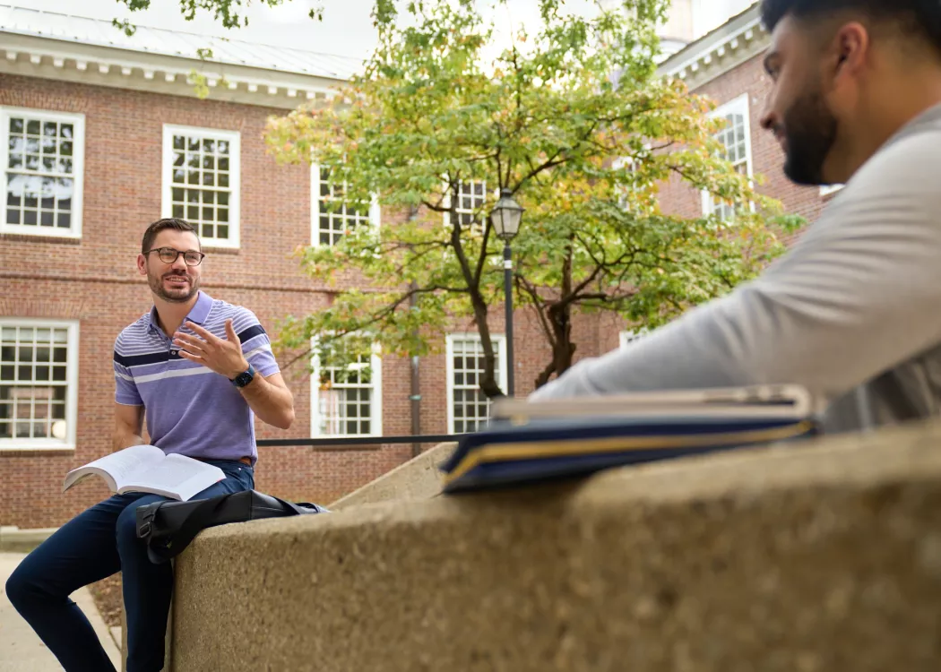 Two students having a socially distanced conversation in the courtyard at the Brandeis School of Law.