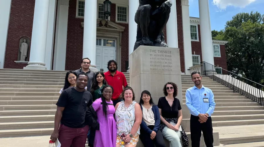 Group of people posing by the Thinker statue.