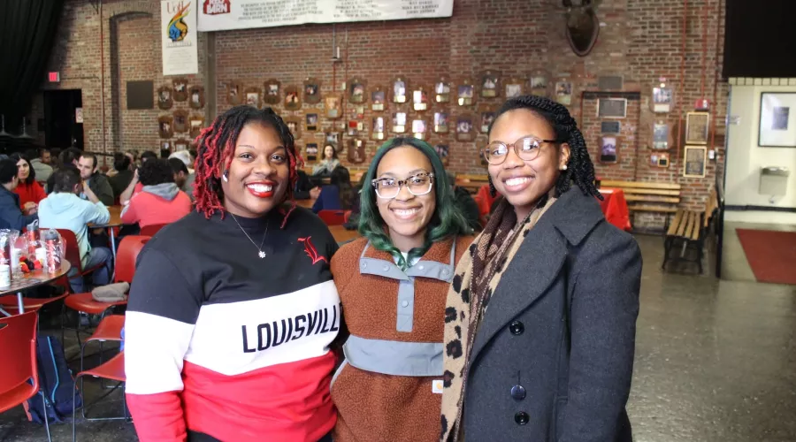 Three graduate students posing at a social event.