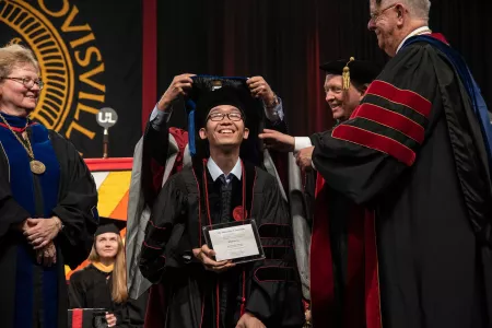 PHD student smiles at the Hooding Ceremony